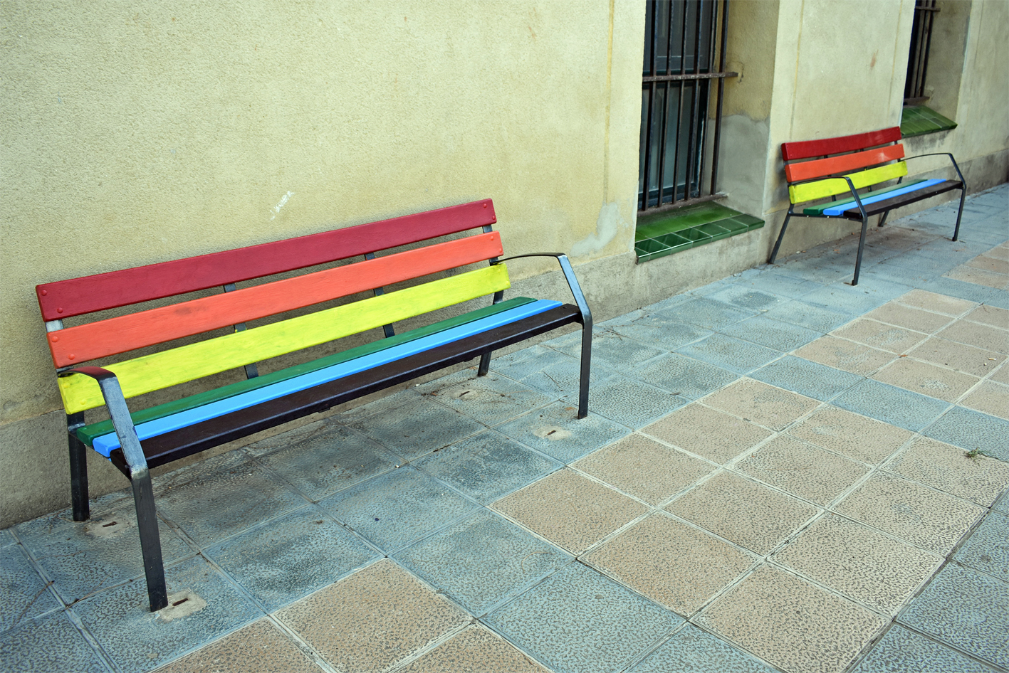 Els Consells Municipals de la Gent Gran i dels Infants pinten dos bancs de la plaça Salvador Perarnau amb els colors del moviment LGTBIQ+