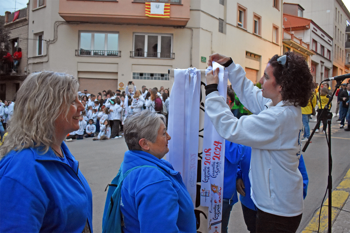 Lliurament de la cinta commemorativa de les Caramelles de SÃºria 2024 a la colla de la Coral SÃ²rissons, en lâ€™acte dâ€™inici de la festa al davant de la Casa de la Vila.