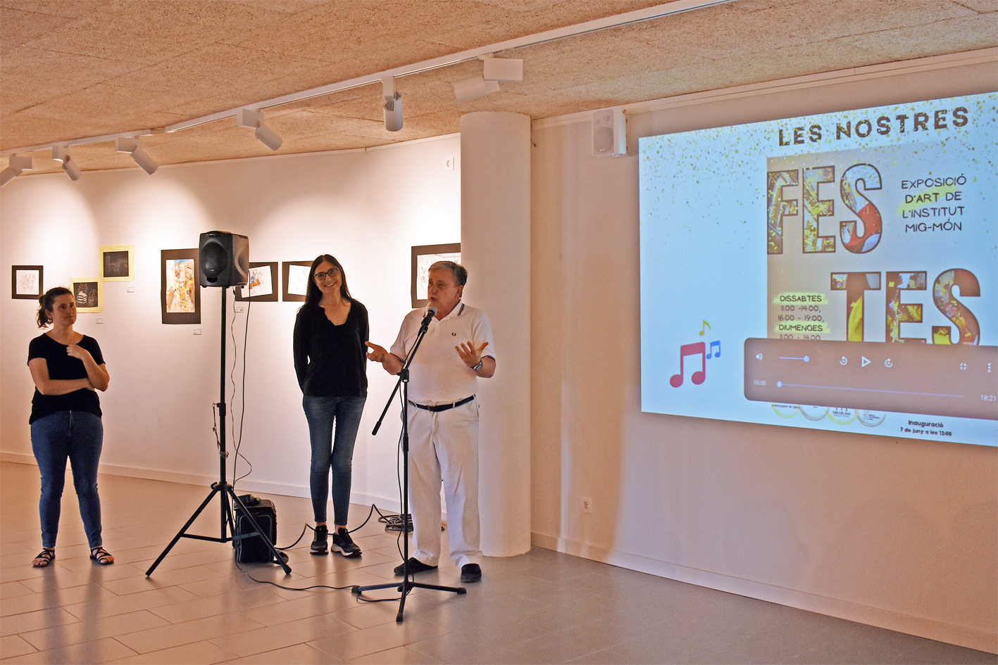 El regidor de Cultura, Albert Fàbrega, parla durant la inauguració de l'exposició 'Les nostres festes' a Cal Balaguer del Porxo, al costat de la directora de l'Institut Mig-Món, Maria Rovira, i de la professora Núria Ros.