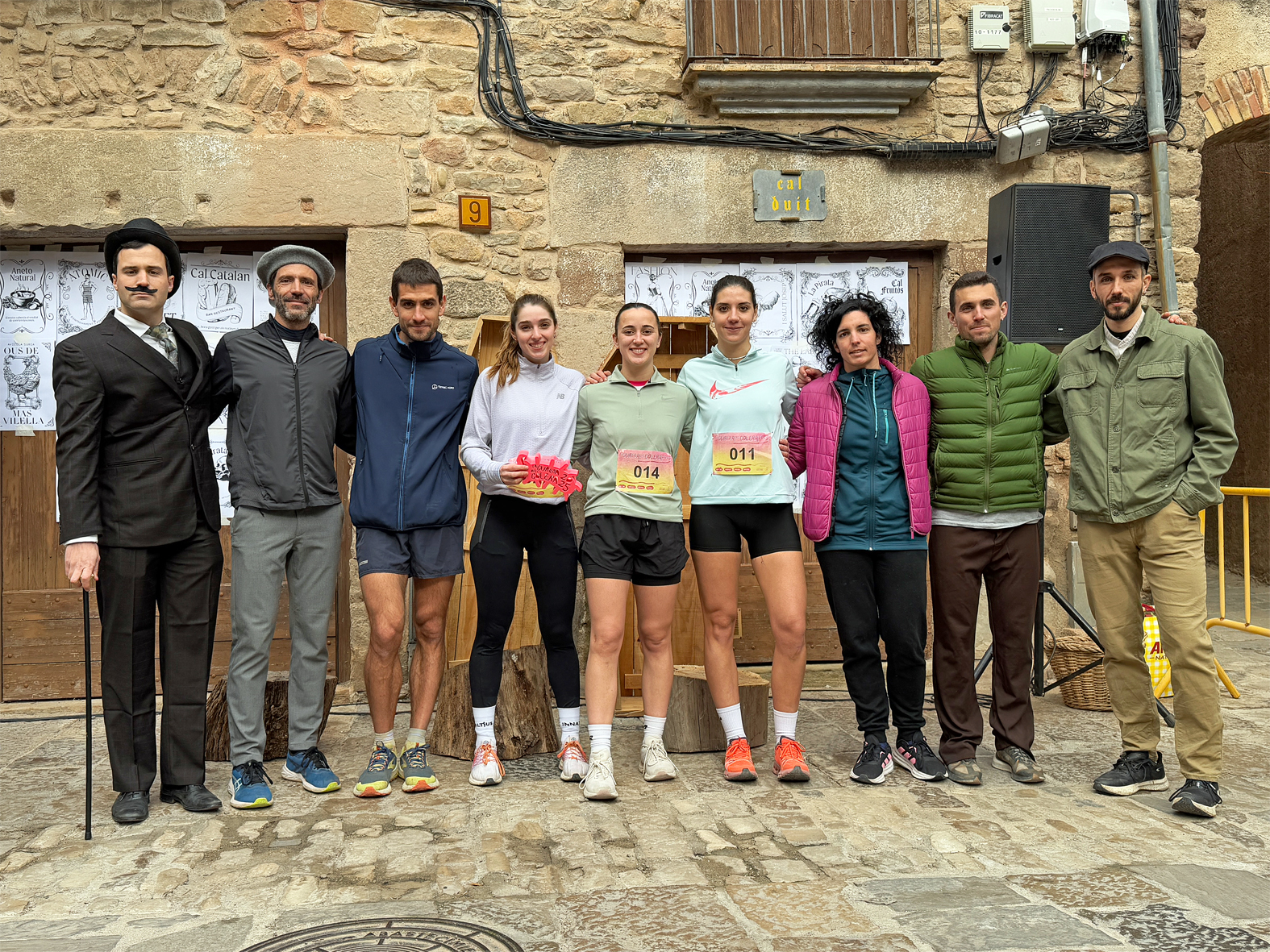 Foto de grup de guanyadors i guanyadores de la Cur(s)a del CÃ²lera al Poble Vell, amb la regidora dâ€™Esports i Festes, Alba MartÃ­nez, i el personatge caracteritzat com lâ€™alcalde del temps de lâ€™epidÃ¨mia, Joan Santamaria.