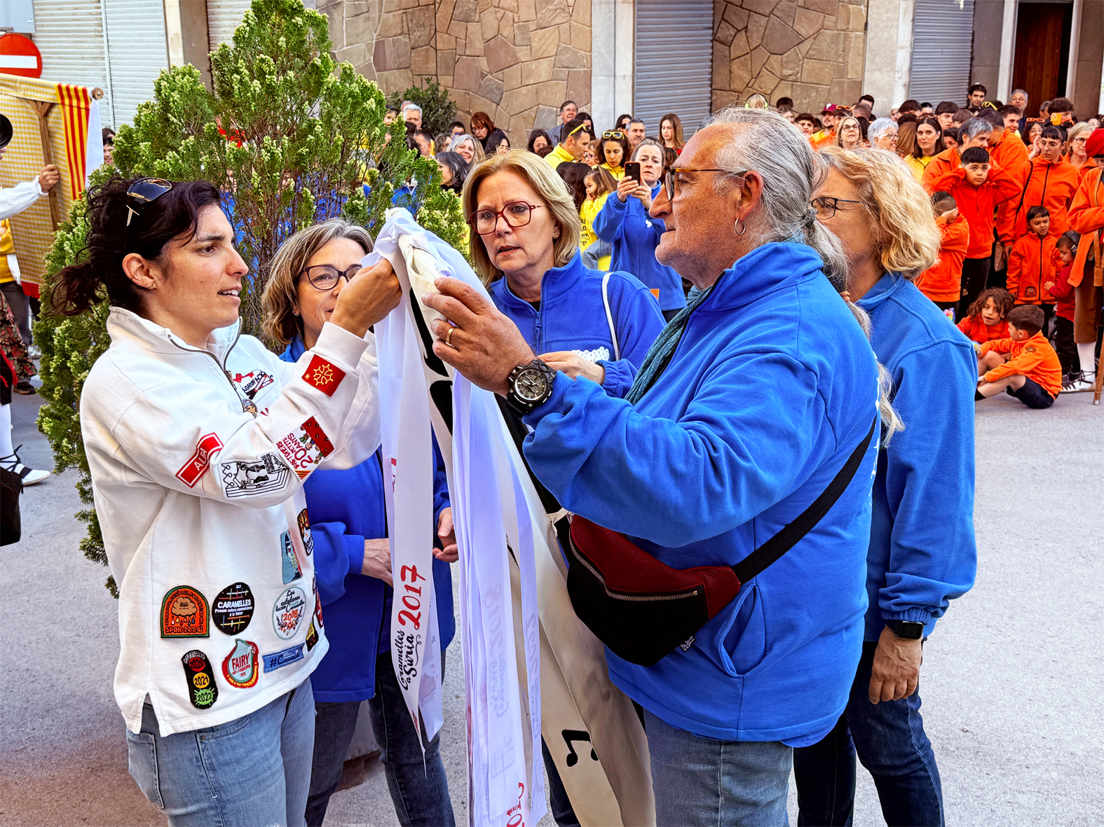 La regidora de Festes, Alba MartÃ­nez, lliura la cinta commemorativa a la colla de la Coral SÃ²rissons en l'acte d'inici de les Caramelles de SÃºria, al davant de la Casa de la Vila.