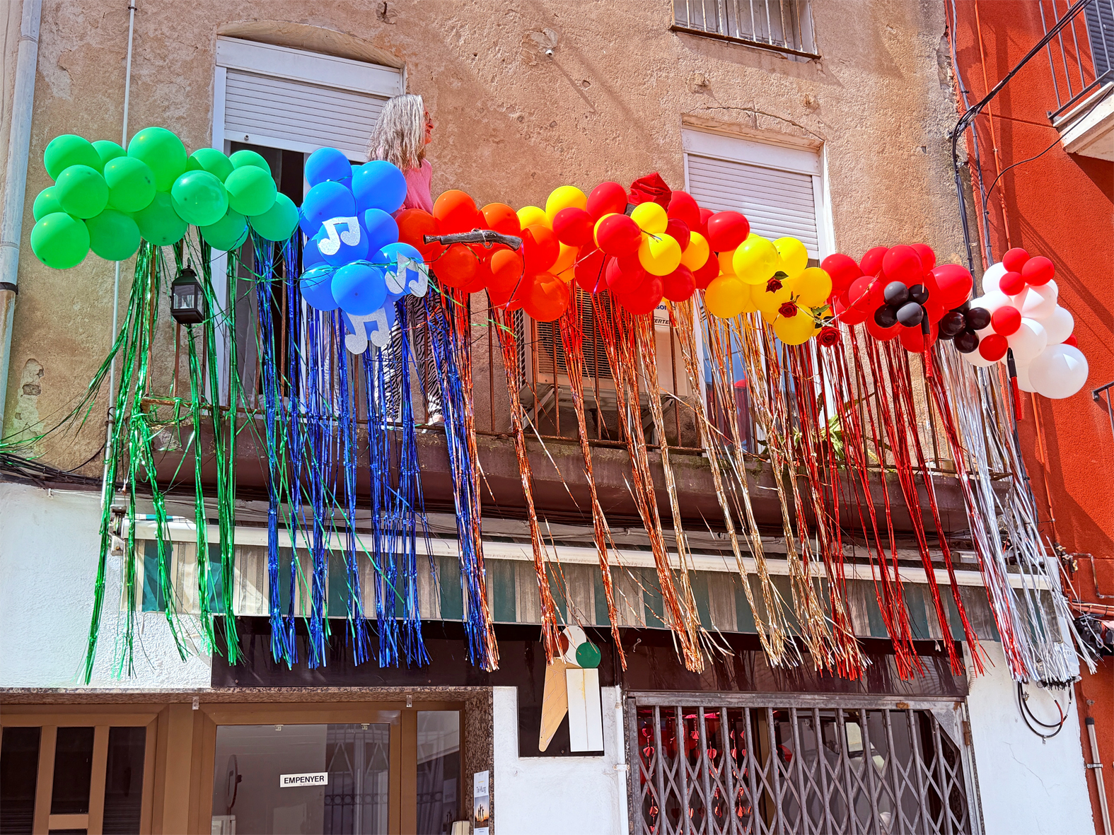 Guarniment d'un balcÃ³ del centre urbÃ  amb els colors i elements identificatius de les colles de les Caramelles de SÃºria 2025.