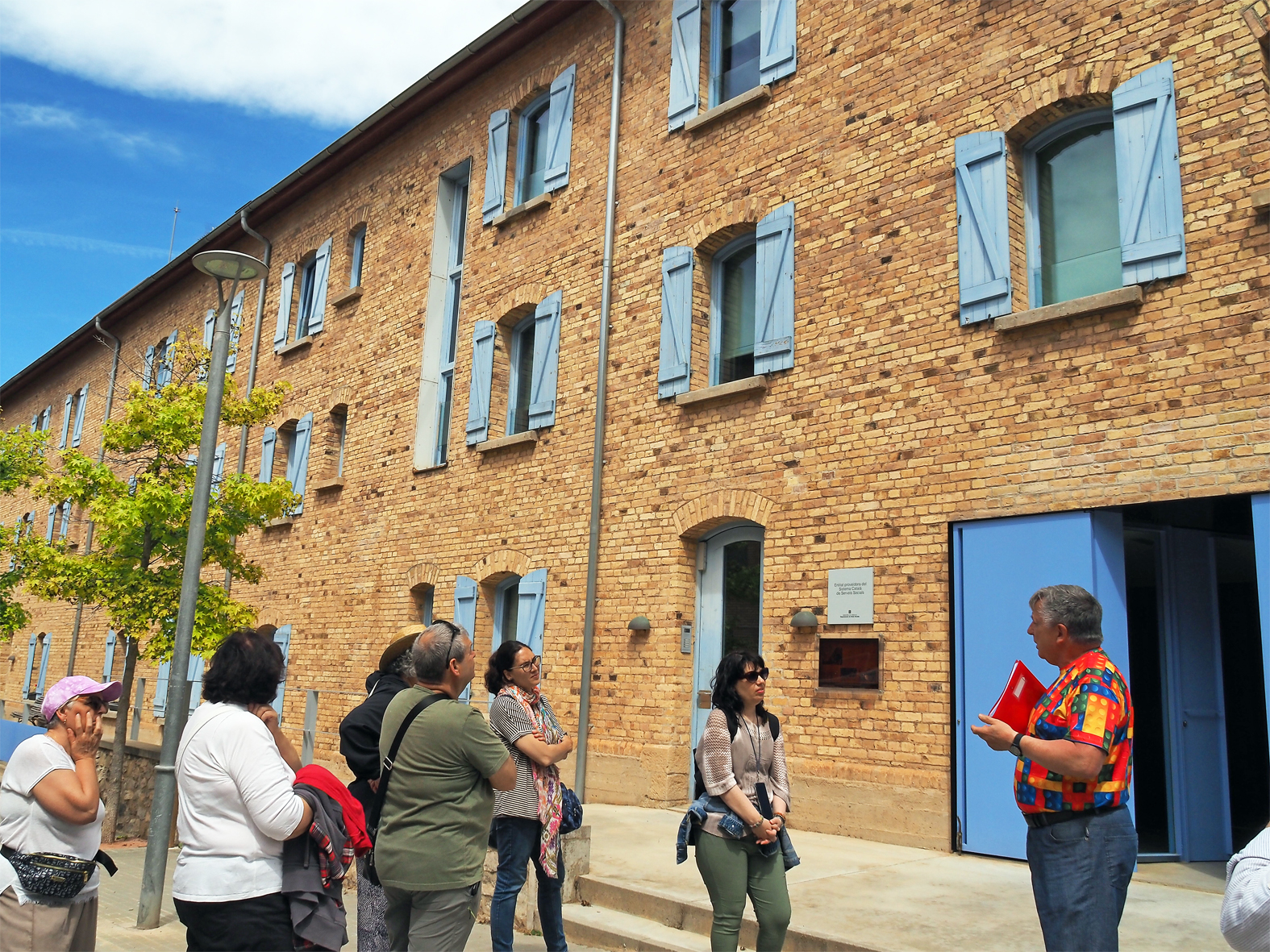 Participants en la visita guiada pel barri de Santa Maria, conduïda per l'estudiós i regidor Albert Fàbrega, al davant del centre d'Ampans, dins de la Setmana Europea dels Geoparcs.
