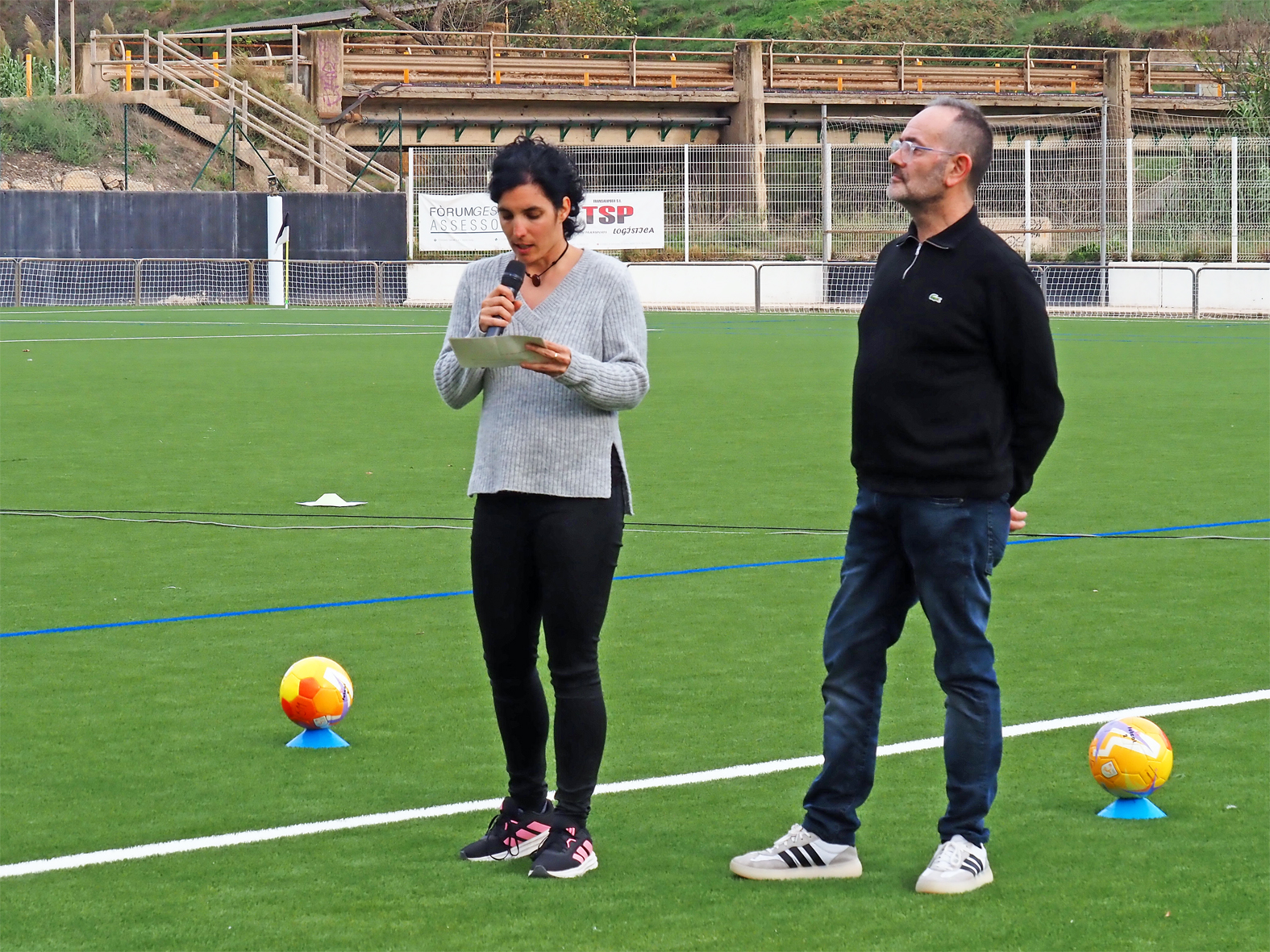 La regidora d'Esports, Alba Martínez, parla durant l'acte de presentació dels equips i inauguració de la nova gespa del Camp Municipal de Futbol de Súria, al costat del president del Centre d'Esports, Lluís Jané.