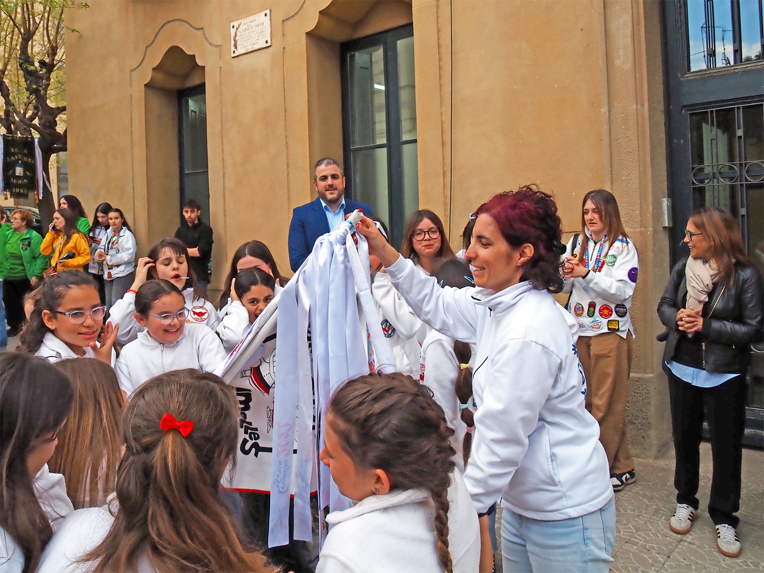 La regidora de Festes, Alba Mart&iacute;nez lliura la cinta commemorativa a la colla Infantil de l'Agrupaci&oacute; Sardanista en l'acte d'inici de les Caramelles de S&uacute;ria, al davant de la Casa de la Vila.