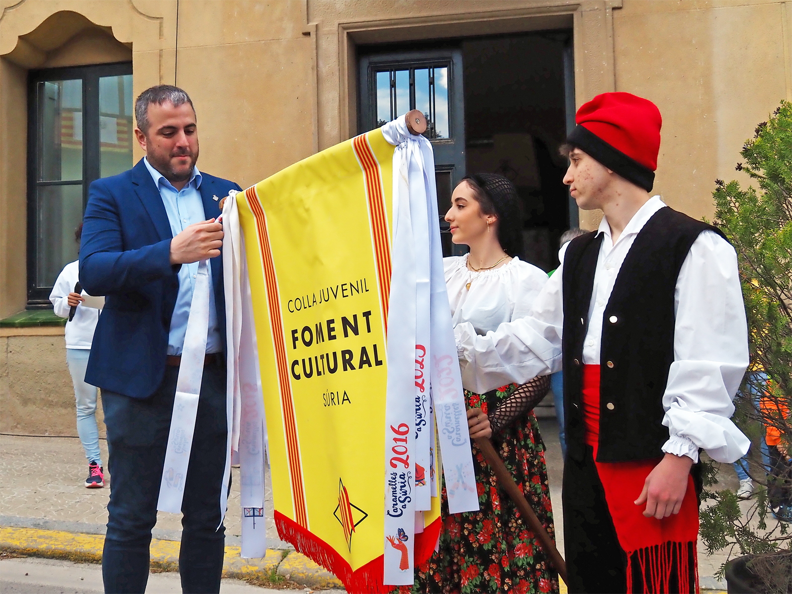 L'alcalde Albert CoberÃ³ lliura la cinta commemorativa a la colla Juvenil del Foment Cultural en l'acte d'inici de les Caramelles de SÃºria, al davant de la Casa de la Vila.