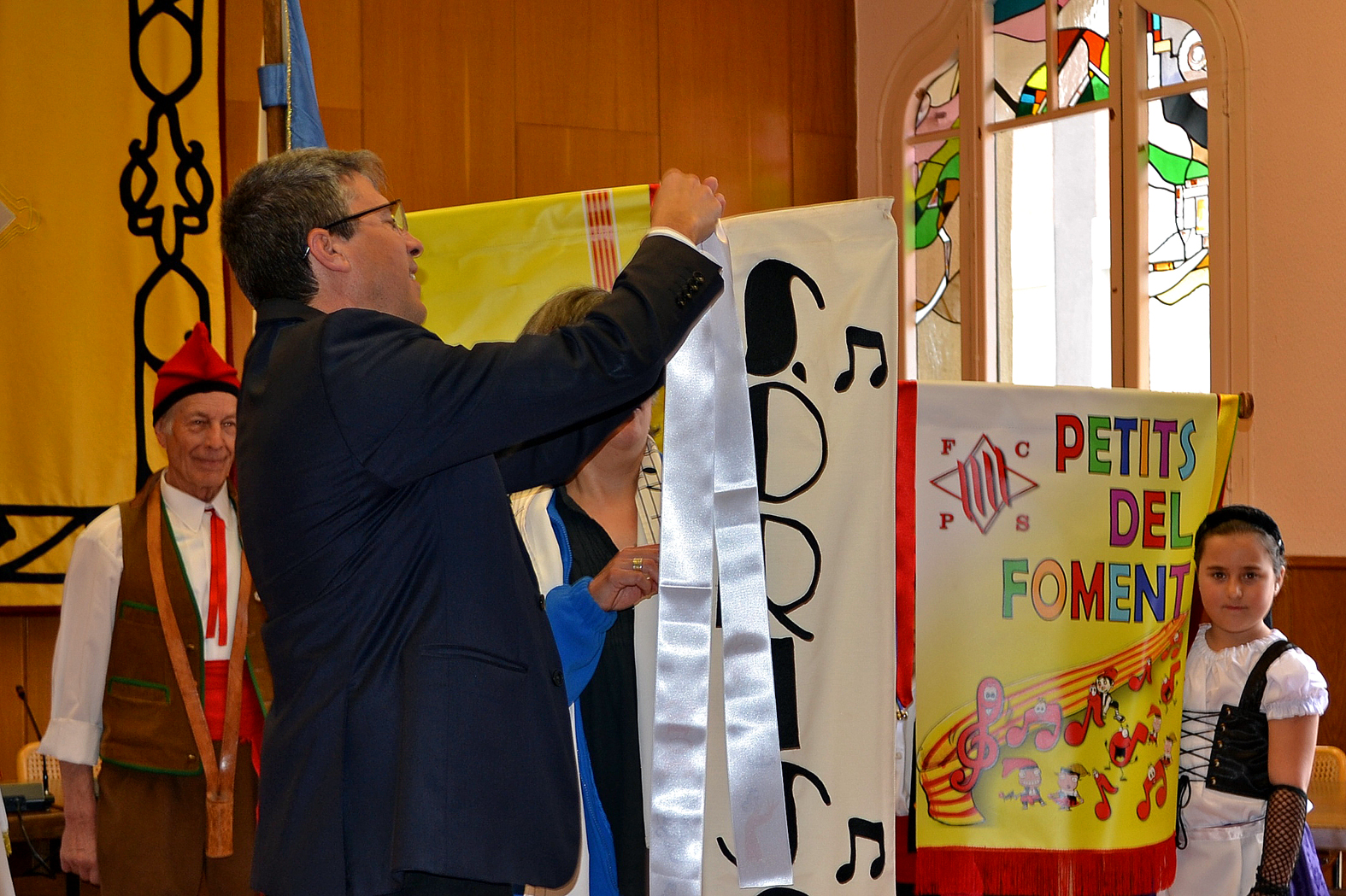 L'alcalde Josep Maria Canudas posa la cinta commemorativa de les Caramelles 2016 a l'estandard de la colla de la Coral SÃ²rissons - MarÃ§ de 2016.