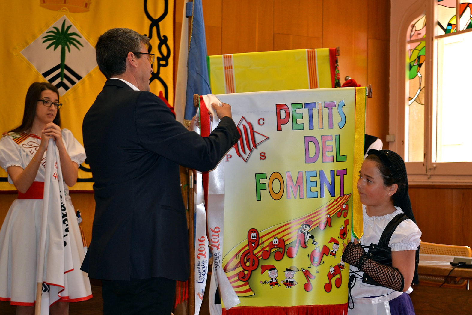 L'alcalde Josep Maria Canudas posa la cinta commemorativa de les Caramelles 2016 a l'estandard de la colla Infantil del Foment Cultural - MarÃ§ de 2016.