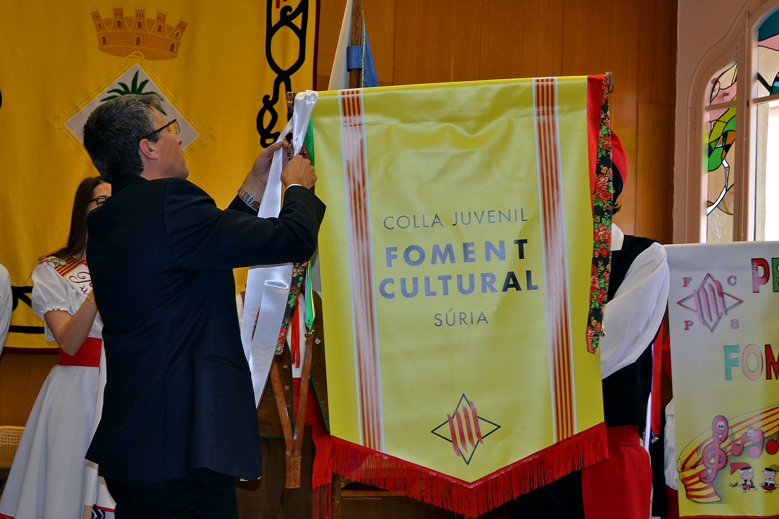 L'alcalde Josep Maria Canudas posa la cinta commemorativa de les Caramelles 2016 a l'estandard de la colla Juvenil del Foment Cultural - MarÃ§ de 2016.