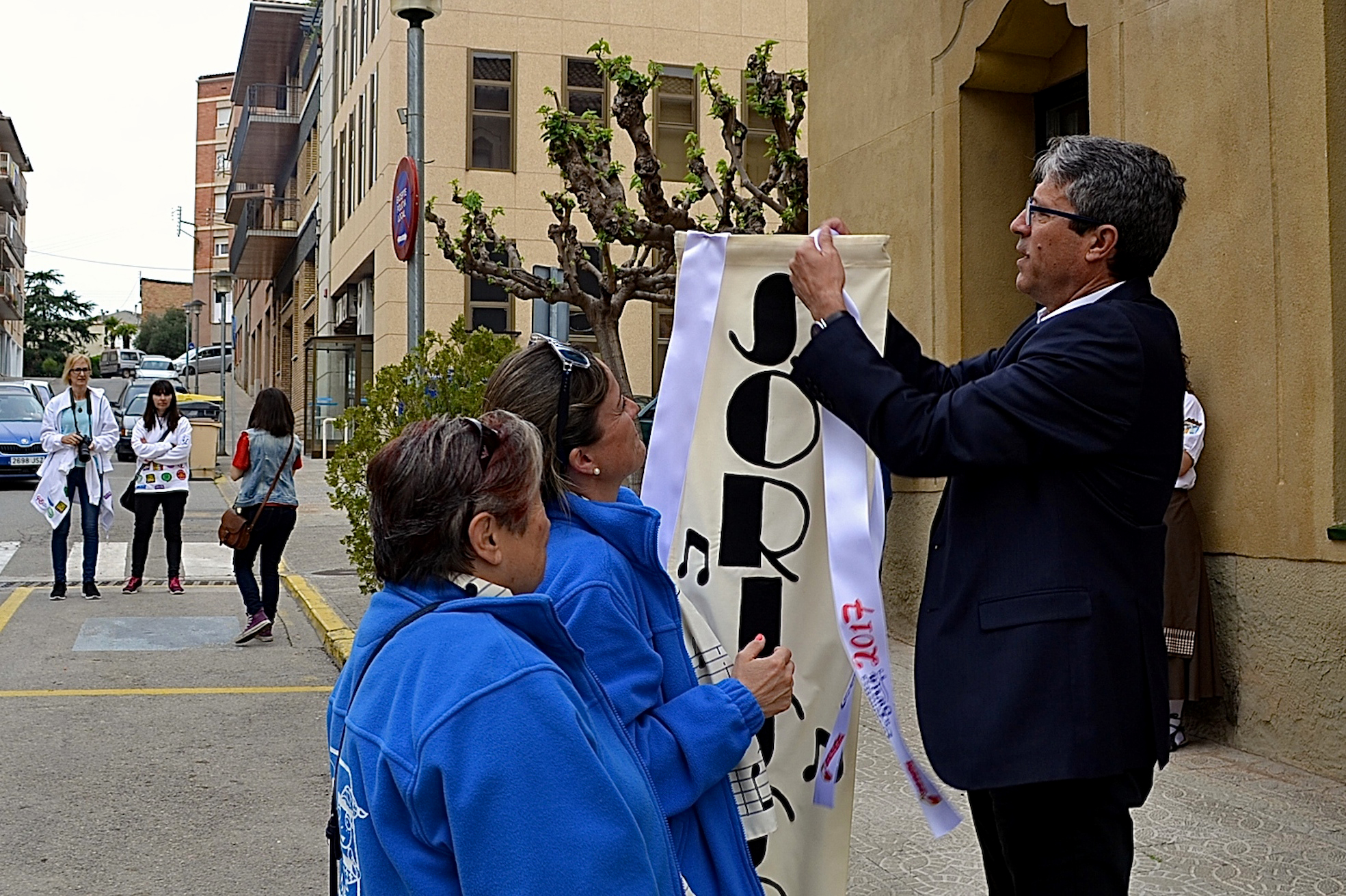 L'alcalde Josep Maria Canudas colâ€¢loca la cinta commemorativa de les Caramelles de SÃºria 2017 en l'estendard de la colla de la Coral SÃ²rissons - Abril de 2017.