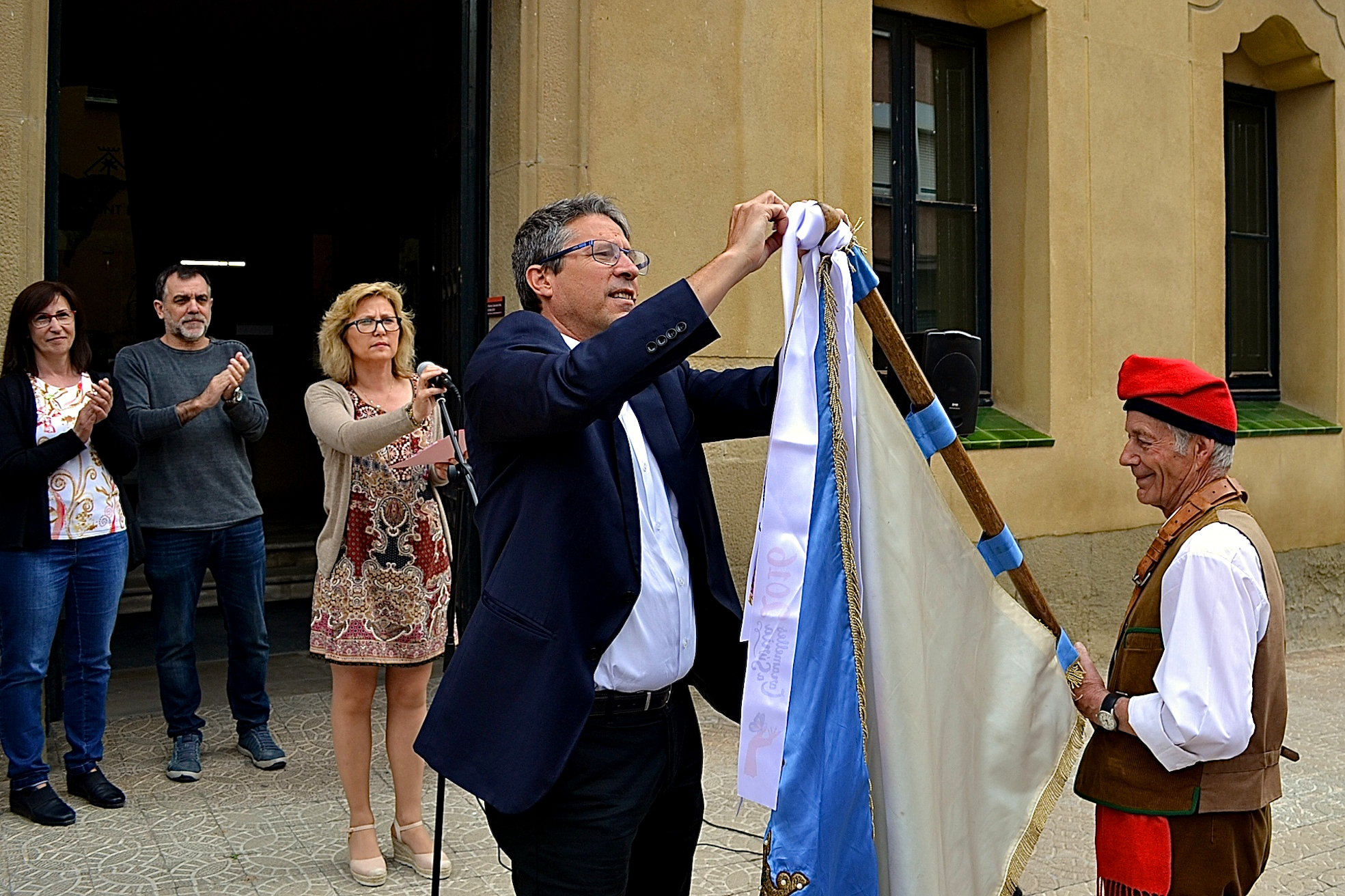 L'alcalde Josep Maria Canudas colâ€¢loca la cinta commemorativa de les Caramelles de SÃºria 2017 en l'estendard de la colla del Tro Gros - Abril de 2017.