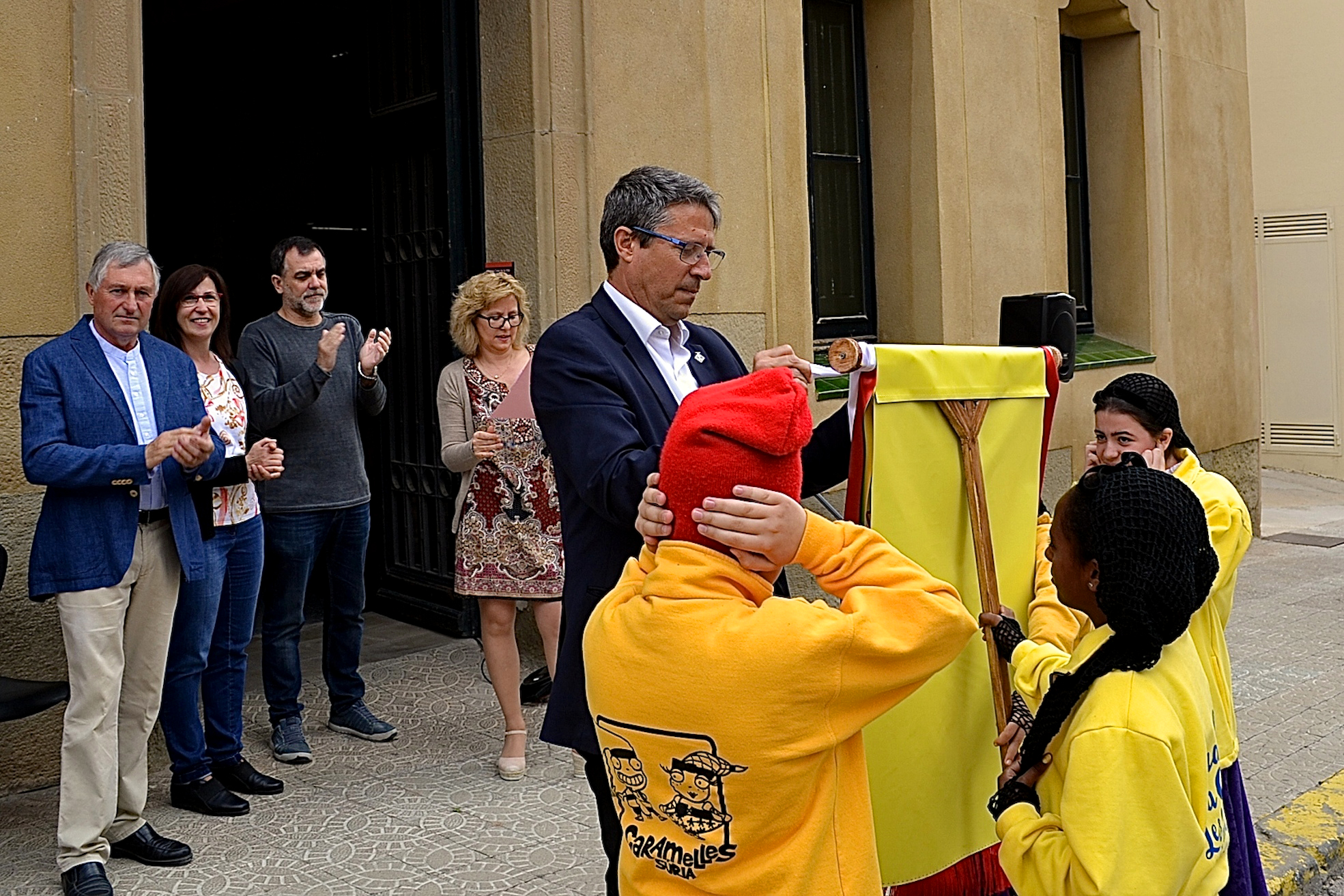 L'alcalde Josep Maria Canudas colâ€¢loca la cinta commemorativa de les Caramelles de SÃºria 2017 en l'estendard de la colla Infantil del Foment Cultural - Abril de 2017.