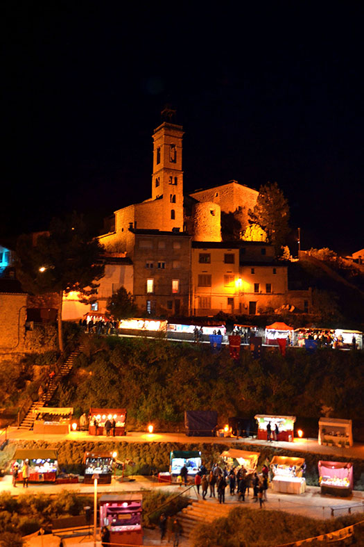 Imatge nocturna de lâ€™EsglÃ©sia i el Castell del Poble Vell de SÃºria amb les parades ubicades a lâ€™espai enjardinat del carrer Campanar, durant la 13a Fira Medieval dâ€™Oficis - Novembre de 2014.