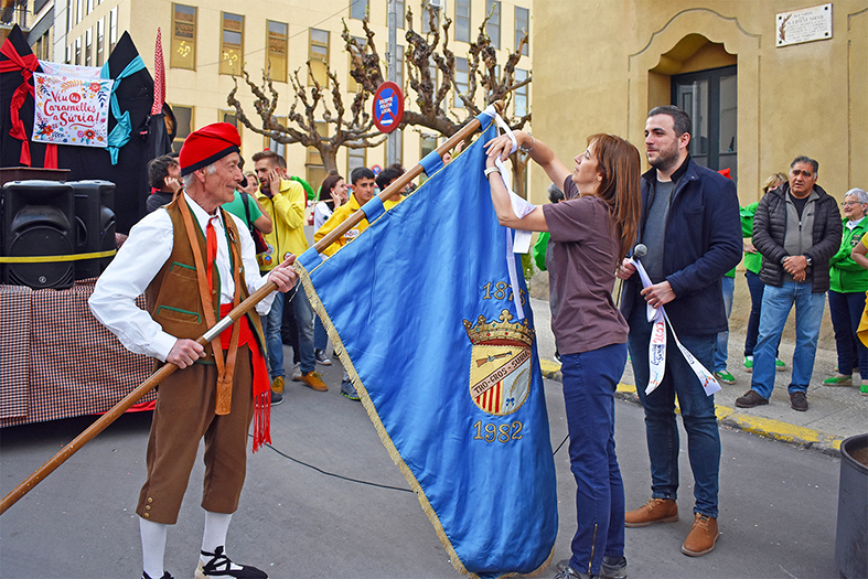 La regidora de Festes, Alba Santamaria, posa la cinta commemorativa de les Caramelles dâ€™enguany a lâ€™estendard de la colla del Tro Gros, durant lâ€™acte dâ€™inici de la festa.