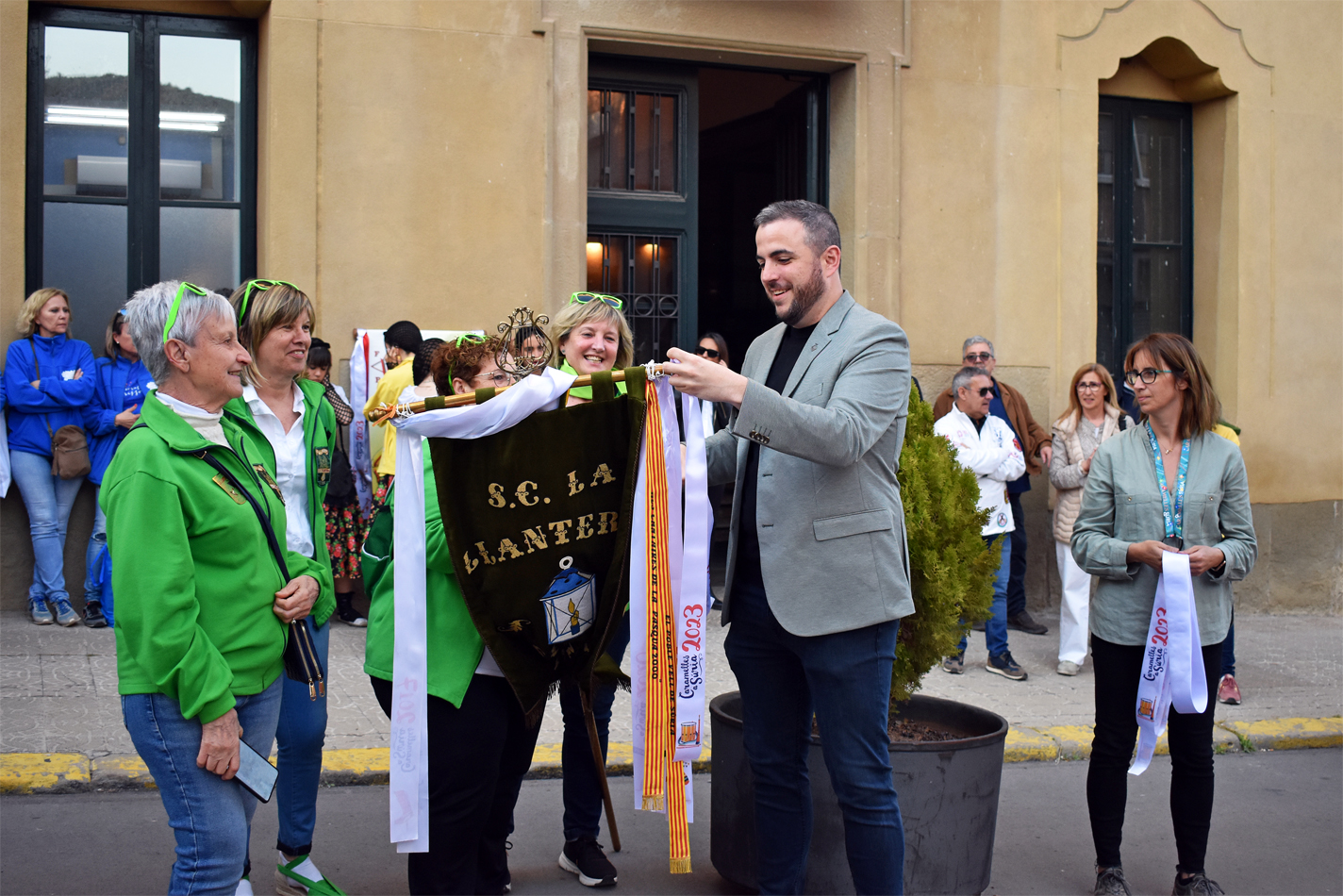 Col·locació de la cinta commemorativa en l'estendard de la Colla de La Llanterna, durant l'acte d'inici de les Caramelles de Súria, al davant de la Casa de la Vila.