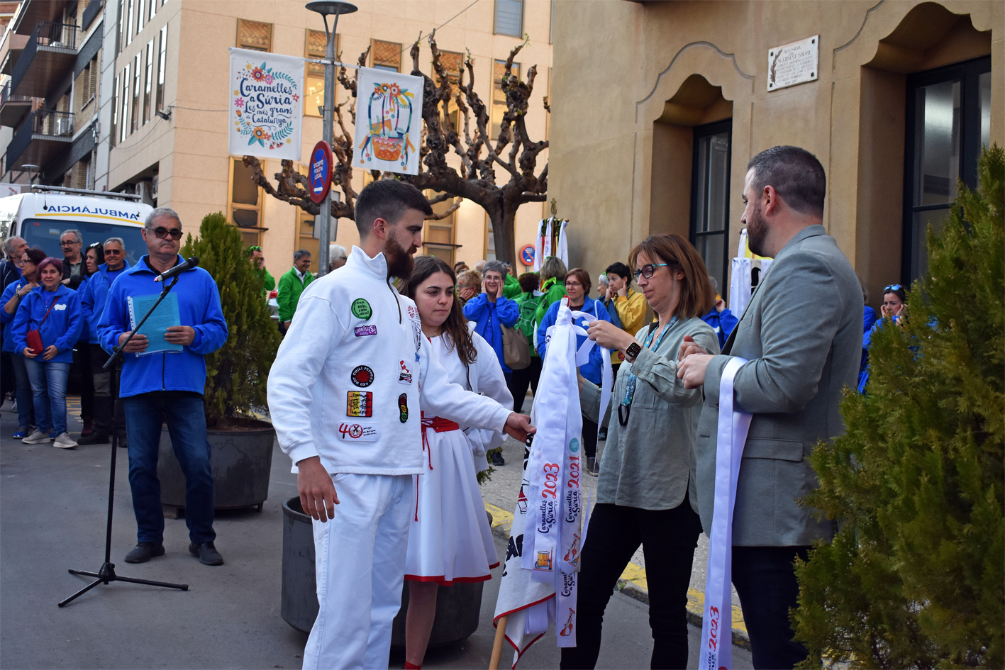 Col·locació de la cinta commemorativa en l'estendard de la Colla dels Grans de l'Agrupació Sardanista, durant l'acte d'inici de les Caramelles de Súria, al davant de la Casa de la Vila.