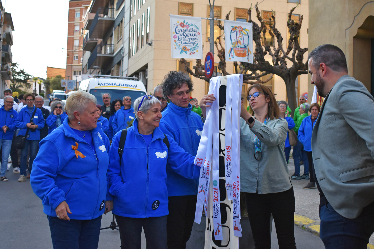 Col·locació de la cinta commemorativa en l'estendard de la Colla de la Coral Sòrissons, durant l'acte d'inici de les Caramelles de Súria, al davant de la Casa de la Vila.