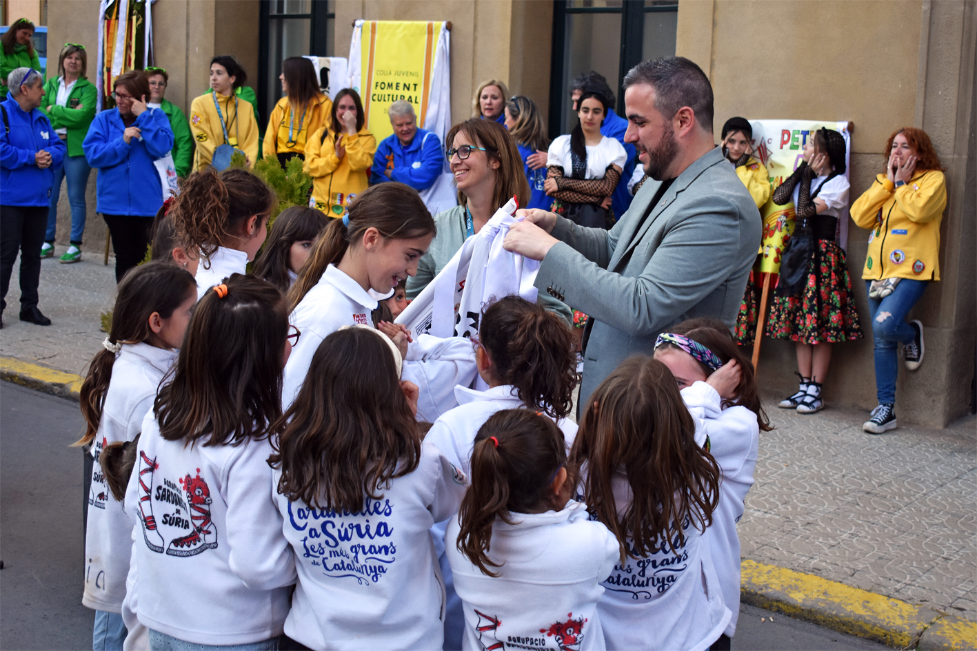 Col·locació de la cinta commemorativa en l'estendard de la Colla Infantil de l'Agrupació Sardanista, durant l'acte d'inici de les Caramelles de Súria, al davant de la Casa de la Vila.