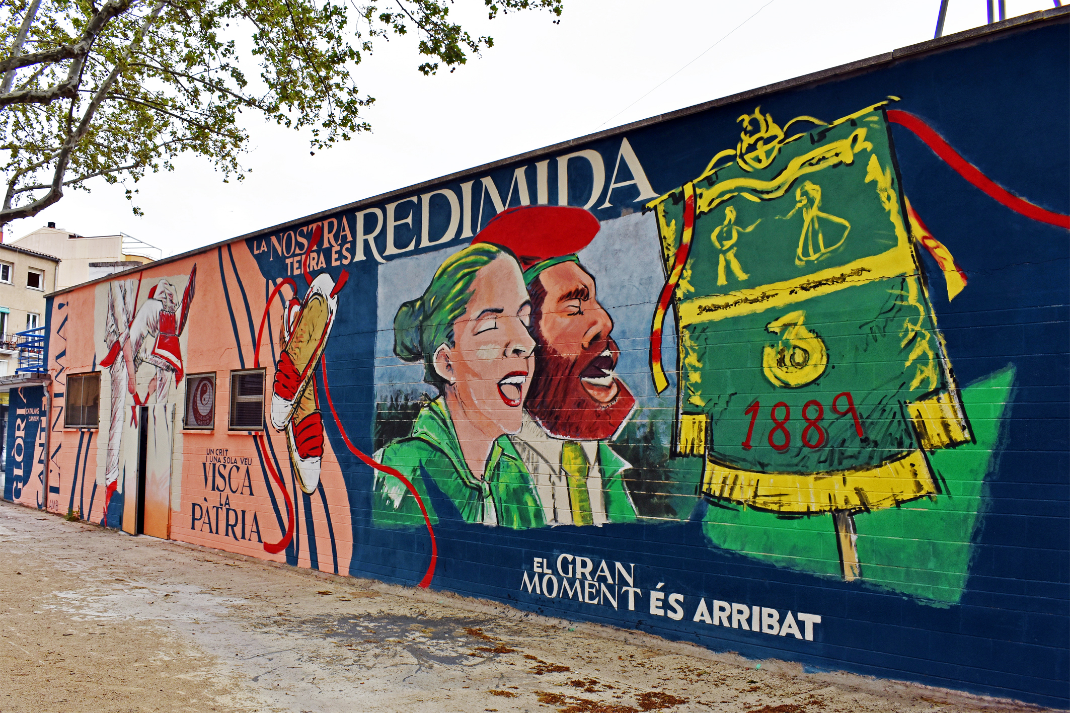 Murals de Caramelles de l'Agrupacio Sardanista i de La Llanterna en una de les façanes de la Piscina Municipal, a l'entorn de la plaça de Sant Joan.